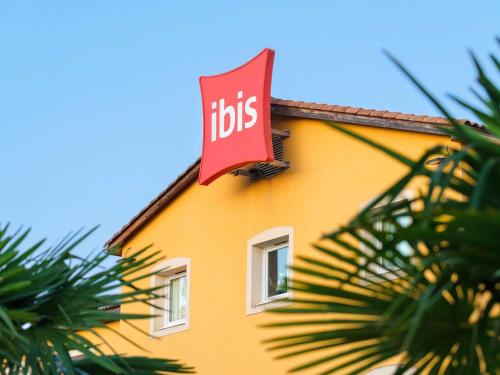 a sign on the side of a yellow building at ibis Manosque Cadarache in Manosque
