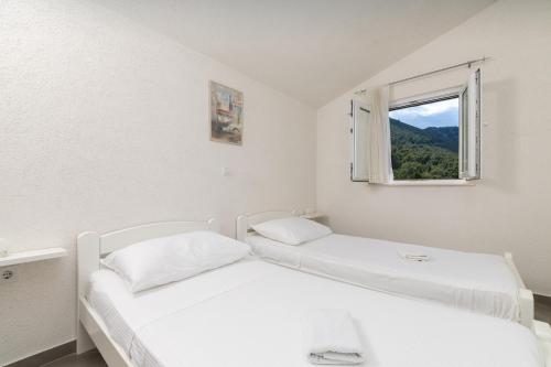 two beds in a white room with a window at Seaside secluded apartments Cove Virak, Hvar - 12321 in Gdinj