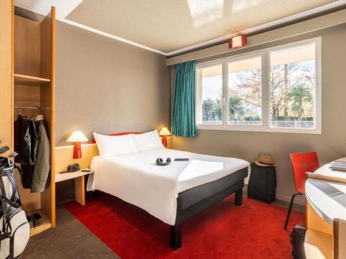 a bedroom with a large white bed and a window at ibis Tarbes Odos in Odos