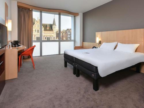 a hotel room with a large bed and a desk at ibis Kortrijk Centrum in Kortrijk