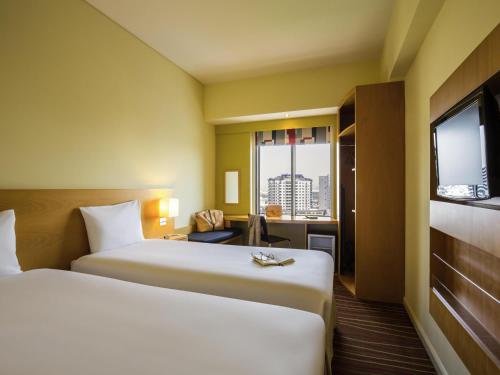 a hotel room with two beds and a window at ibis Deira Creekside Dubai in Dubai