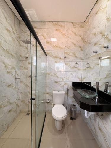 a bathroom with a toilet and a glass shower at Fonsecas House Suíte Privativas in Paraguaçu