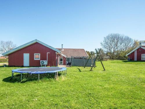 a trampoline in a yard in front of a red barn at 4 star holiday home in Nordborg in Nordborg