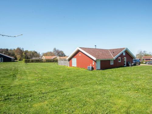 a red house in the middle of a green field at 4 star holiday home in Nordborg in Nordborg