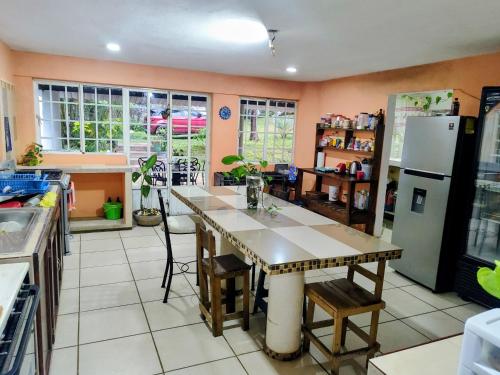 a kitchen with a table and a refrigerator at EL Jardin De Los Anturios in Xico
