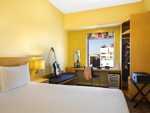 a bedroom with a bed and a desk with a chair at ibis Dubai Al Rigga in Dubai