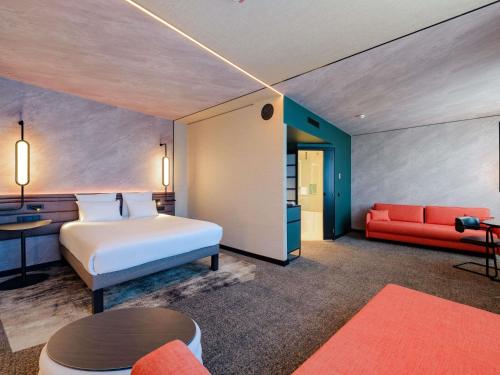 a hotel room with a bed and a red couch at Novotel München Airport in Freising