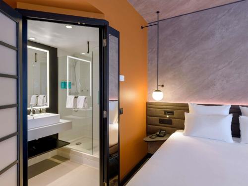 a hotel room with a bed and a bathroom at Novotel München Airport in Freising
