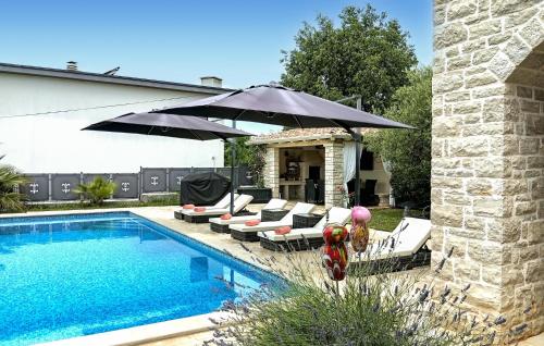 a pool with lounge chairs and an umbrella next to a pool at Villa Ginocchetti in Kaštelir