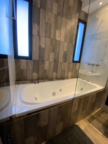 a bathroom with a tub and a sink and two windows at Complejo Terranova in Aimogasta