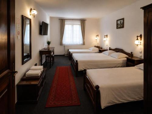 a hotel room with four beds and a red rug at Millenium Castle Sibiu - Parking on Site - BIKERS' Haven in the Heart of Romania's Legendary Roads - Rest in Comfort # in Sibiu