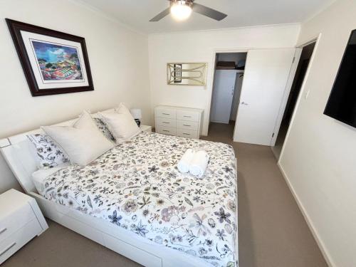a small bedroom with a bed with a floral bedspread at Jubilee Apartment 14 in South West Rocks