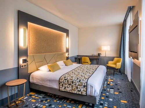 a hotel room with a bed and two chairs at Hôtel Mercure Rodez Cathédrale in Rodez