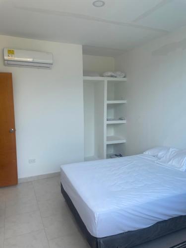 a bedroom with a white bed and a book shelf at Casa Sol & Descanso Tocaima in Tocaima