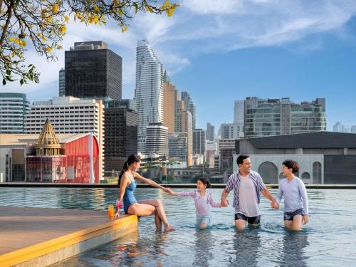 a family playing in the water in the city at Novotel Bangkok Platinum Pratunam in Bangkok