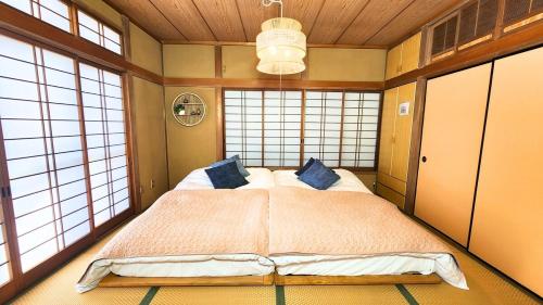 a bedroom with a large bed in a room with windows at 足利すまいるハウス in Ashikaga