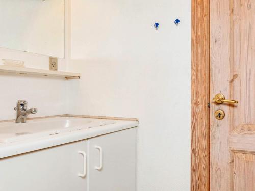 a white bathroom with a sink and a door at Lush holiday home in Thyholm in Thyholm