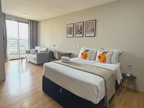 a bedroom with a large bed and a living room at Franklin Studio Prime Rio Energy - Piscina, Sauna, Academia in Rio de Janeiro