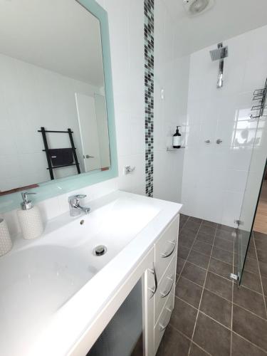 a white bathroom with a sink and a mirror at Esplanade Bliss in Cronulla