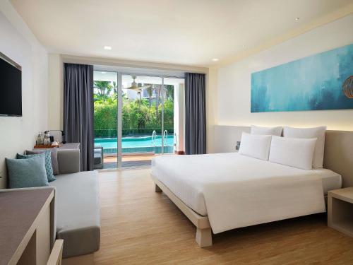 a bedroom with a large white bed and a pool at Pullman Pattaya Hotel G in North Pattaya