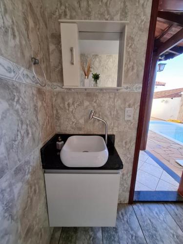 a bathroom with a white sink and a mirror at Casa c Piscina em Holambra in Holambra