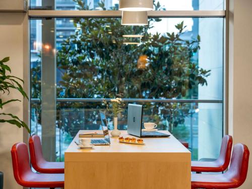 an office with a desk with a laptop and red chairs at ibis Adana in Adana