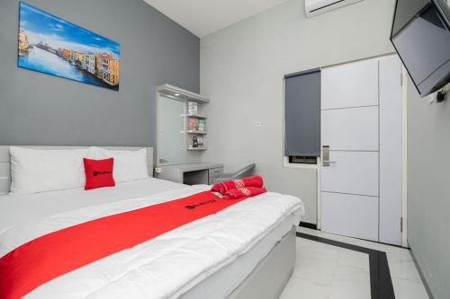 a bedroom with a large white bed with red pillows at RedDoorz Plus near Politeknik Negeri Malang in Malang