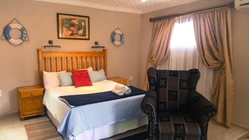 a bedroom with a bed and a chair and a window at Aark Guest Lodge in Vanderbijlpark