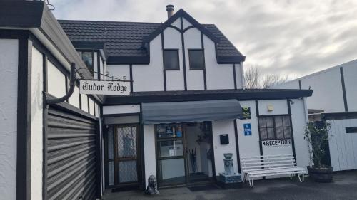a white building with a sign that reads center living at Tudor Lodge Motel in Nelson