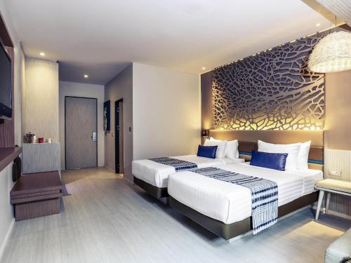 a hotel room with a large bed with blue pillows at Mercure Koh Chang Hideaway in Ko Chang