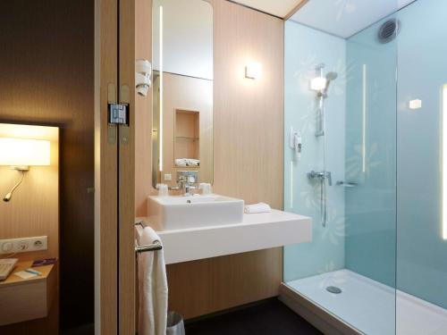 a bathroom with a sink and a glass shower at Mercure Valenciennes Centre in Valenciennes