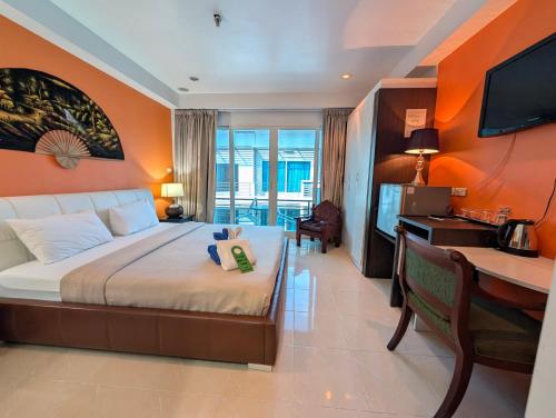 a bedroom with a bed and a desk with a computer at Access Inn Pattaya in Pattaya