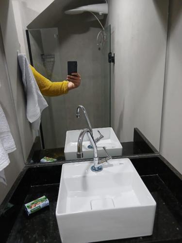 a person taking a picture of a sink in a bathroom at Loft Meu Aconchego in Nova Friburgo