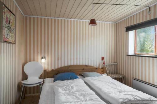 a bedroom with a large bed and a white chair at 20103-Samso-Teglvaerksvej-2 in Brundby