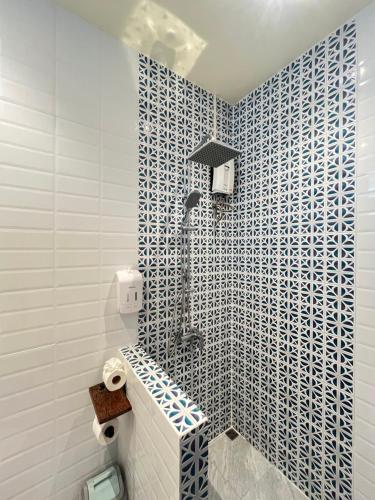 a bathroom with a shower with blue and white tiles at Benjamin's Hut in Srithanu