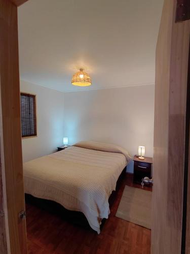 a small bedroom with a bed and a light at Cabaña Los Cactus en Mamalluca in El Durazno