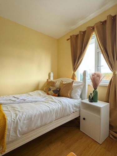 a bedroom with a bed with white sheets and a window at Erris house in Belmullet