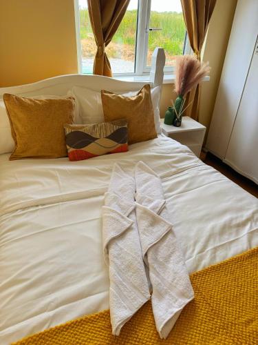 a white bed with some pillows and a window at Erris house in Belmullet