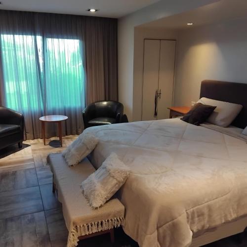 a bedroom with a large white bed and chairs at VICTORIA BED and BREAKFAST 1 A 3KM AEROPUERTO EZEIZA in Ezeiza