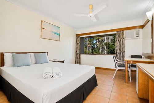a bedroom with a bed with two shoes on it at The Reef Motel in Cairns