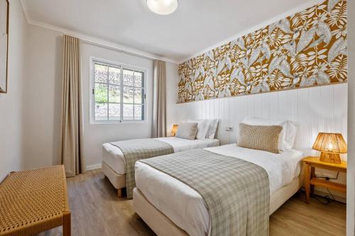 two beds in a hotel room with a painting on the wall at Sunlit Apartment with Balcony & Atlantic Views in Ponta do Sol