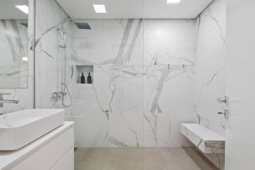 a white bathroom with a shower and a sink at Sunlit Apartment with Balcony & Atlantic Views in Ponta do Sol