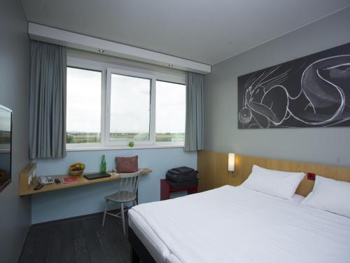 a hotel room with a bed and a desk at Ibis Vienna Airport in Schwechat