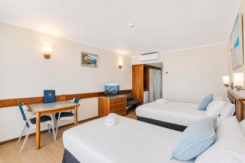 ein Hotelzimmer mit zwei Betten und einem Schreibtisch in der Unterkunft The Oceanfront in Cairns