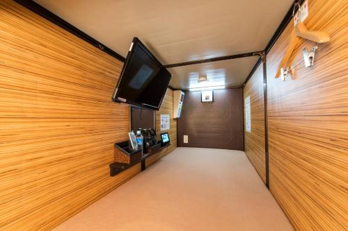 a hallway with a flat screen tv on a wooden wall at Anshin oyado Tokyo Man Akihabara in Tokyo