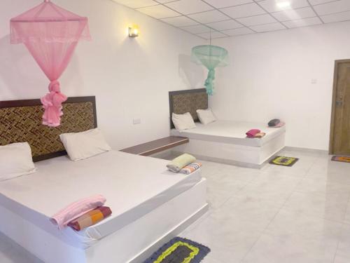 two beds in a room with pink and blue decorations at Velora Resort in Udawalawe