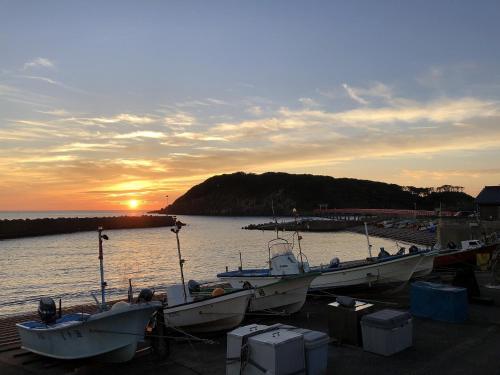 a group of boats docked at a dock with the sunset at 東尋坊近く自転車無料 コンビニ目の前1ルーム貸切 in Mikuni