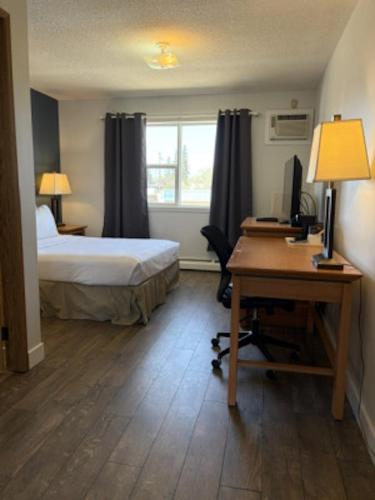a bedroom with a bed and a desk with a computer at Rimbey Motor Inn in Rimbey