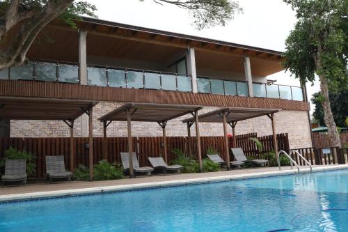 a swimming pool with chairs and a building at Big Blue Sodwana Bay in Sodwana Bay