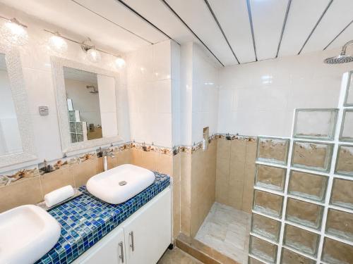 a bathroom with a sink and a mirror and a shower at Beachfront condo with loft and sea views in Puerto Aventuras